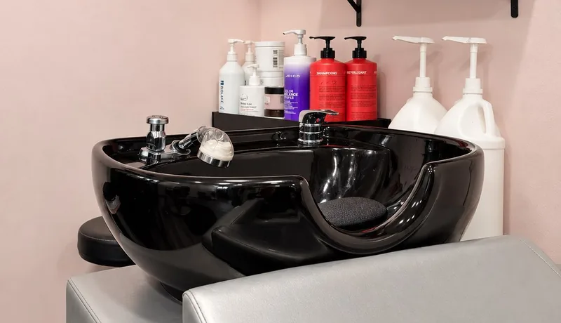 Black shampoo basin and colour products against the pink wall