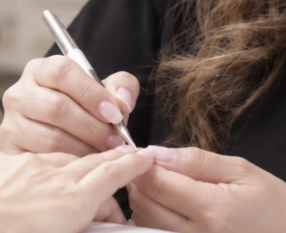 Nicole hand-painting a nail with a fine brush